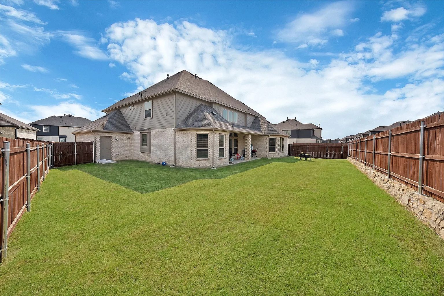Fenced lawn behind the home, with the rear exterior and covered patio visible.