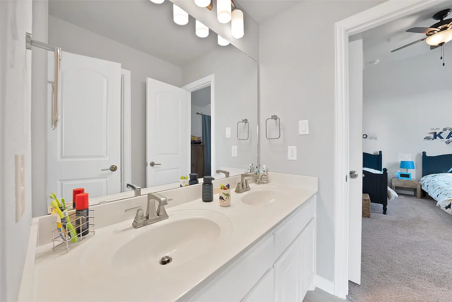 Bathroom with a double vanity and a doorway toward another room.