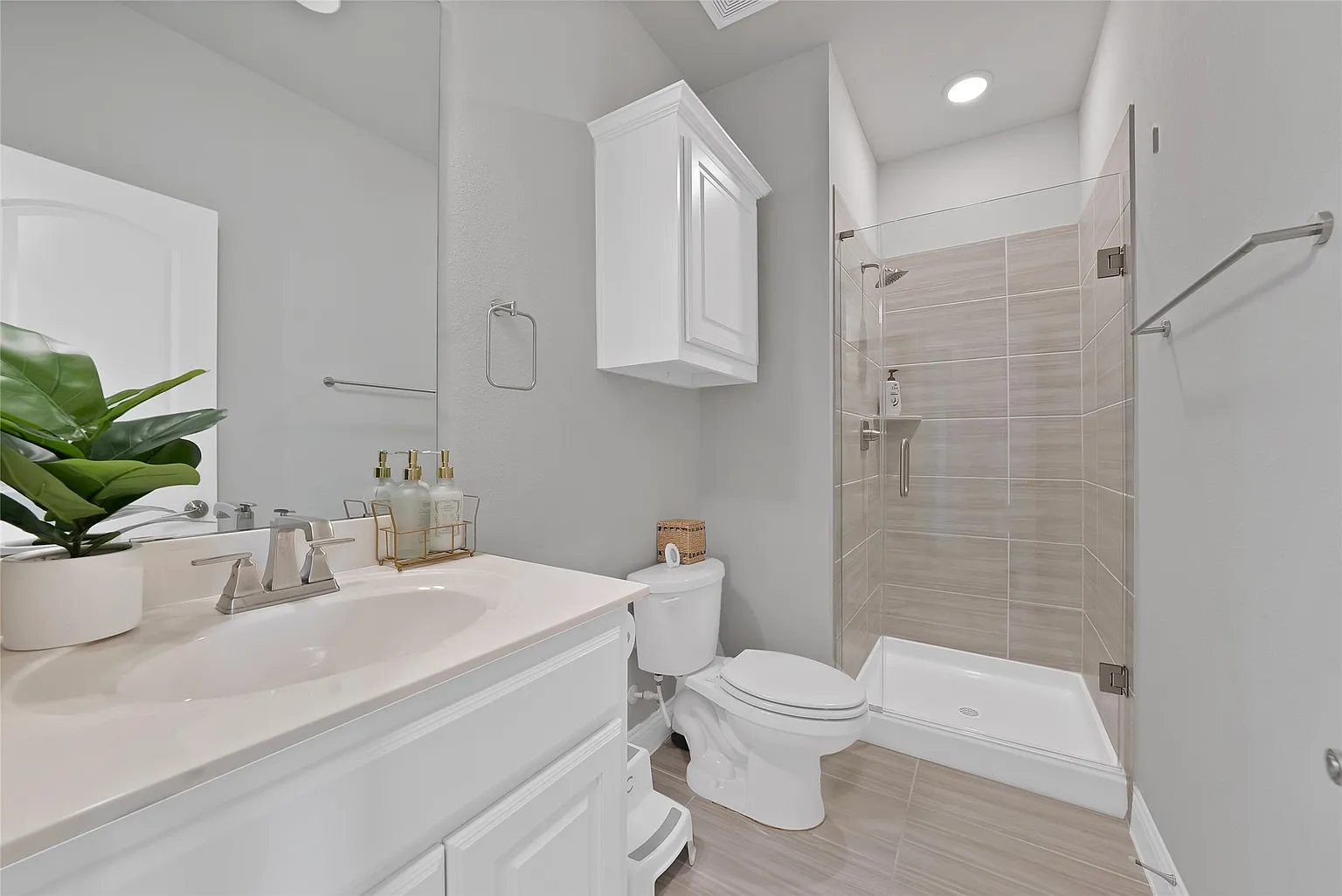Bathroom with a vanity and separate tiled shower.
