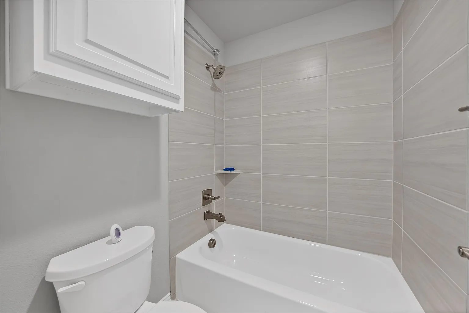 Bathroom with a bathtub and tiled shower surround.
