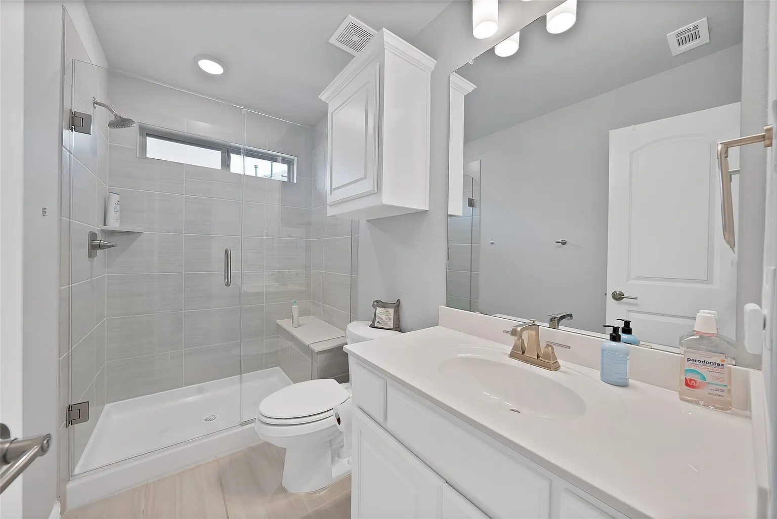 Bathroom vanity, mirror and tub with shower surround.