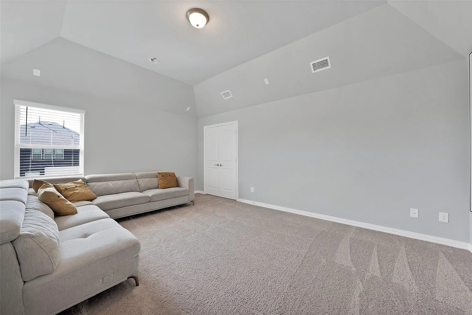 Carpeted flexible-use room with a sectional sofa and open floor area.