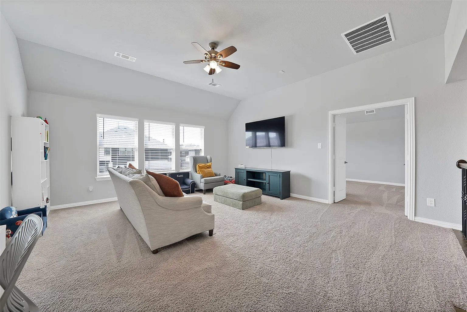 Large carpeted upstairs living area with seating, television and windows.