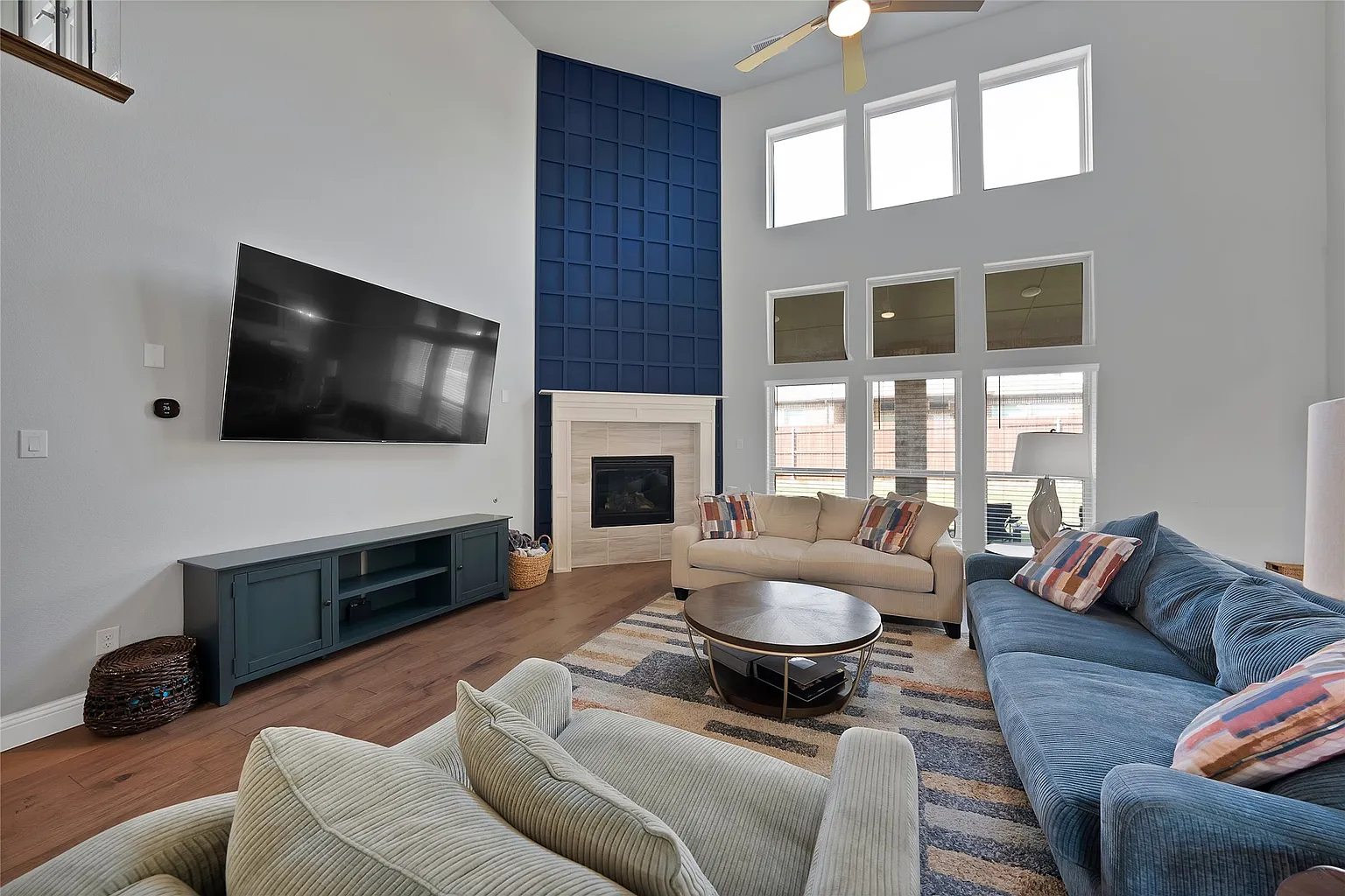 Living area with tall windows, fireplace and blue accent wall.