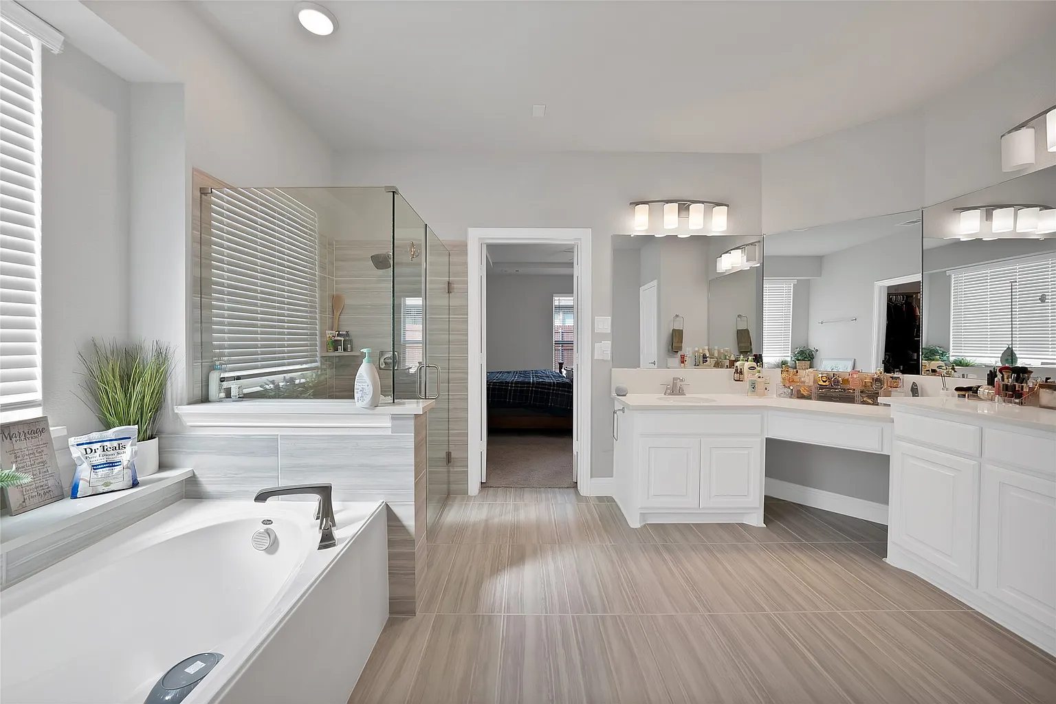 Primary bathroom showing vanities, tub and glass shower.